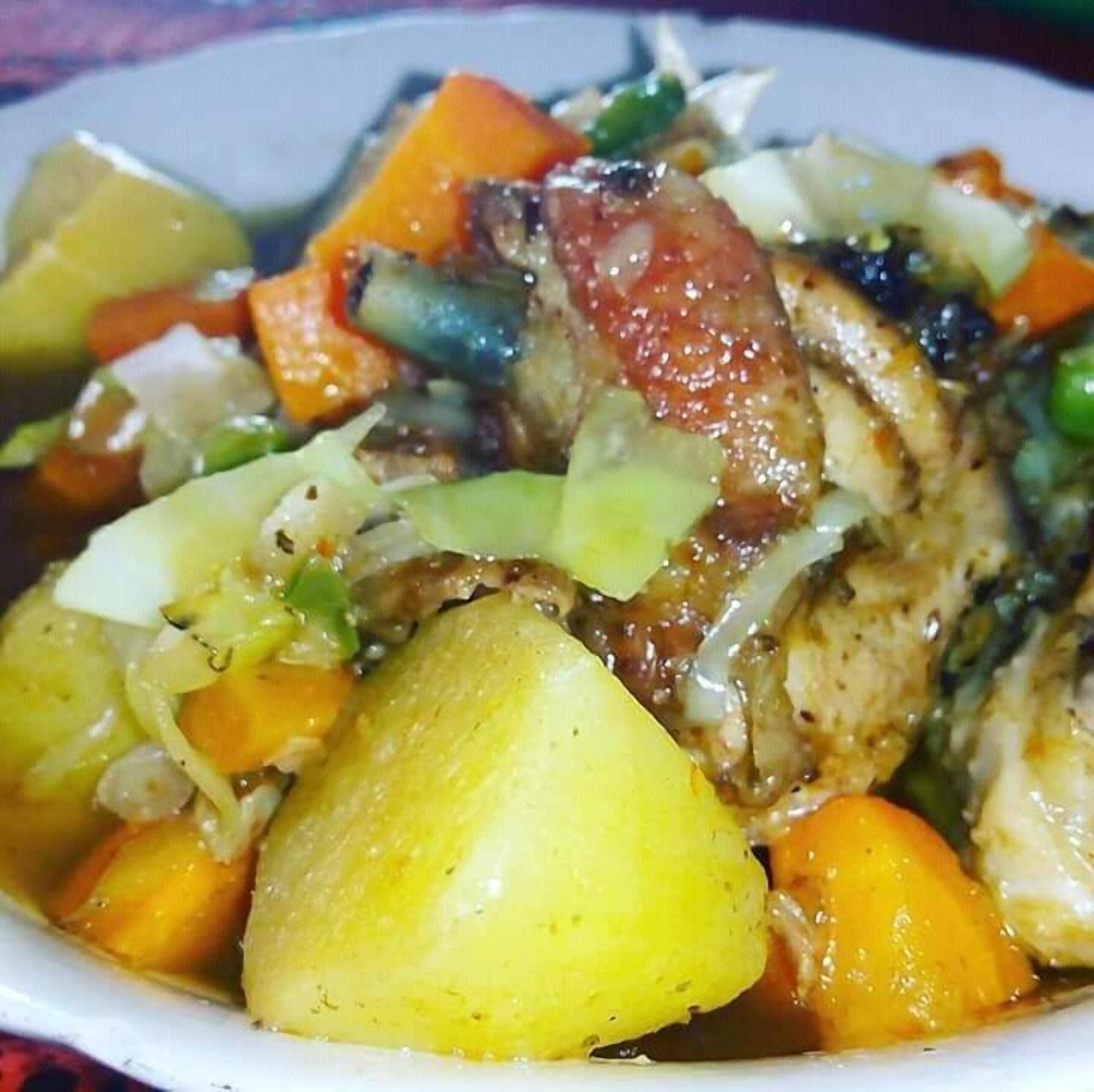 Primer plano de un plato con pollo, papas, zanahorias y col.