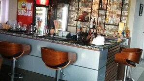 Zona de bar con mostrador, taburetes y una pared decorada con diversos objetos.