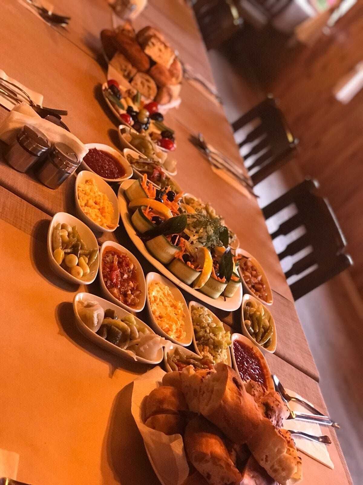 Une longue table à manger, dressée avec différents plats et accompagnements.