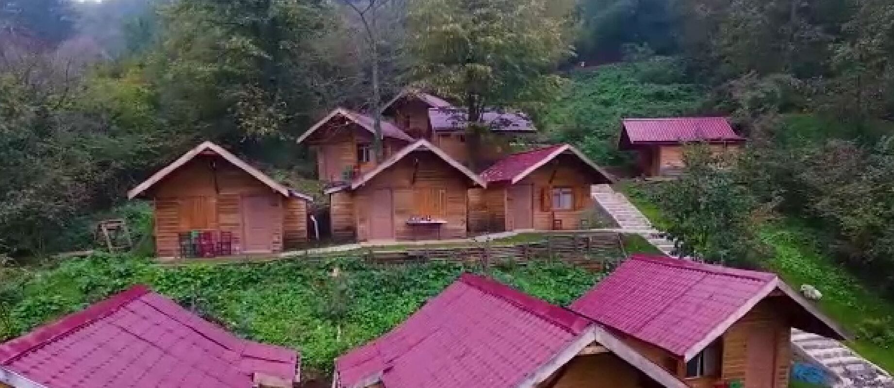 Un ensemble de chalets en bois aux toits rouges, entourés d’une végétation luxuriante.