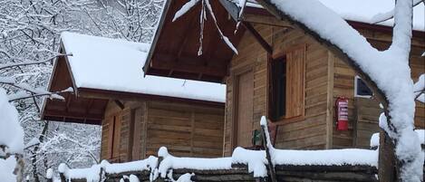 Una cabaña de madera con techo nevado y un extintor de incendios colgado en la pared.