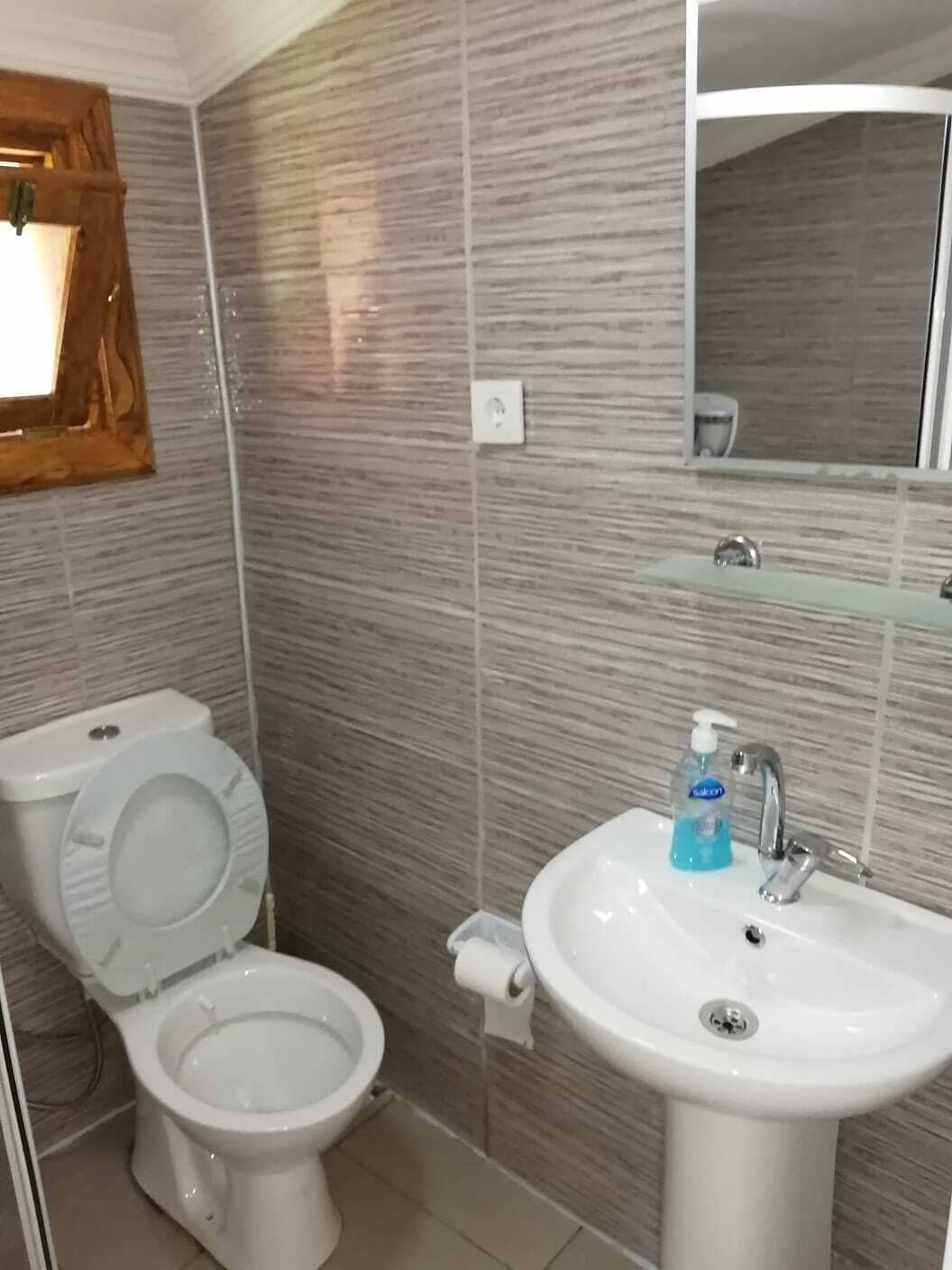 Une salle de bain avec deux toilettes, un lavabo et un miroir.