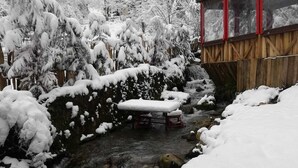 A wooden cabin with a red roof and glass windows, situated beside a snow-covered stream. - Yesil Dus Vadisi Bungalow Restoran (Kartepe)