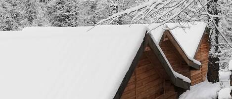 A wooden cabin with a snow-covered roof and a wooden exterior wall.