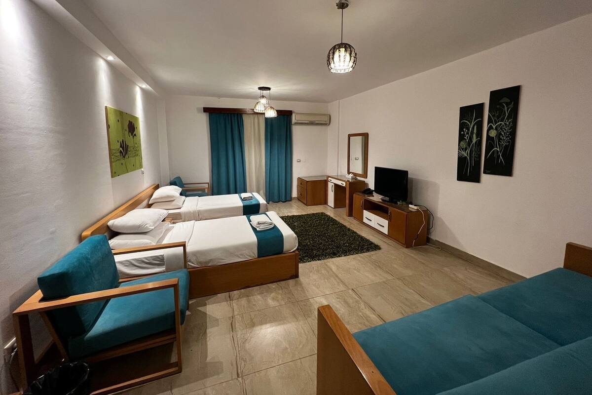 Een hotelkamer met twee eenpersoonsbedden, een bank, een televisie, een bureau en een spiegel.