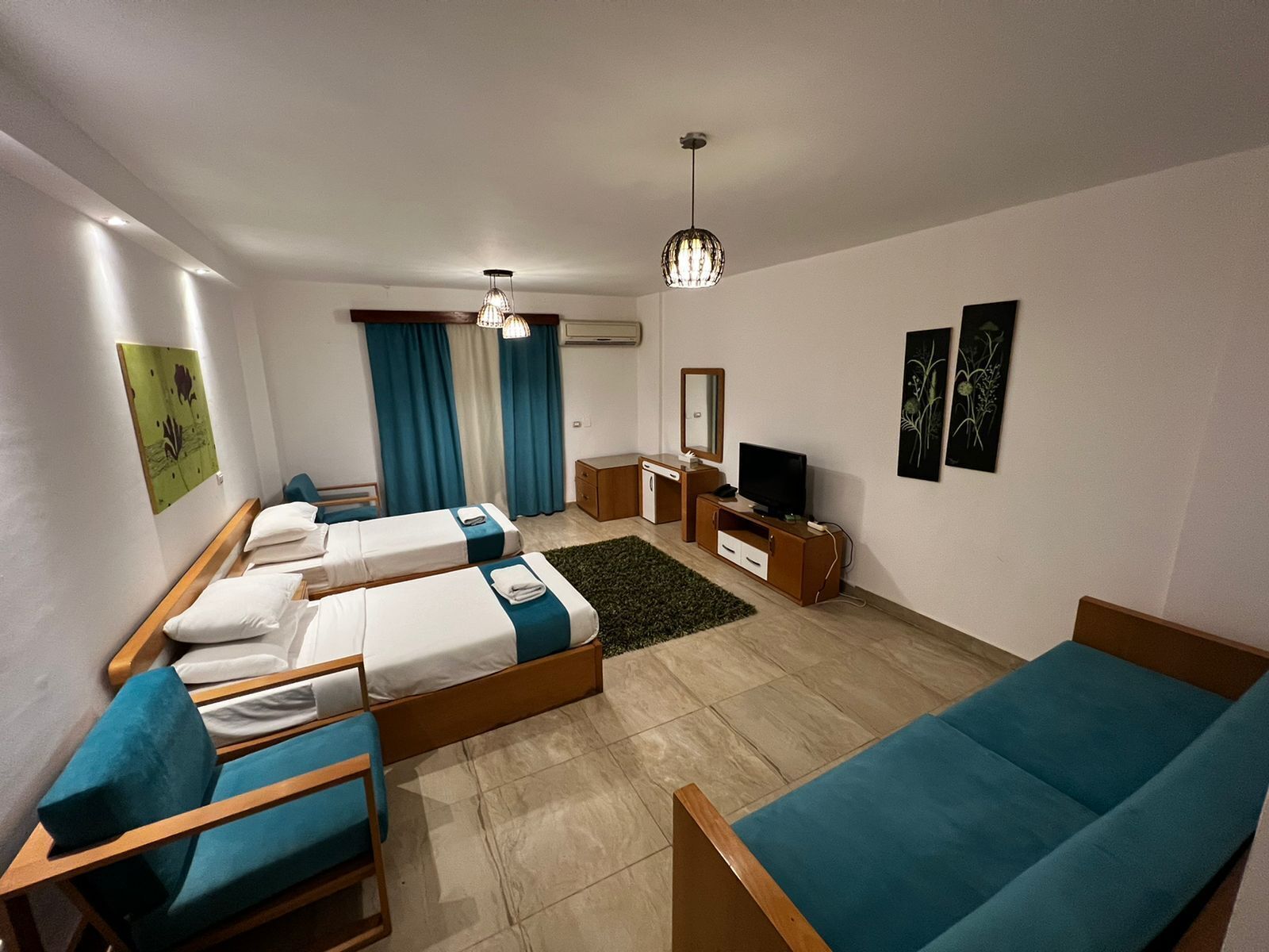 Una habitación de hotel con dos camas individuales, un sofá, un televisor y un escritorio pequeño.