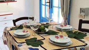 Un coin repas avec une table dressée pour deux personnes, agrémenté d’une nappe à motifs et d’une porte bleue en arrière-plan.