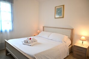 A neatly made bed with white linens and towels, a bedside lamp, and a framed picture on the wall. - 4-Bedroom Villa Near the Beaches of Costa Rei (Costa Rei)