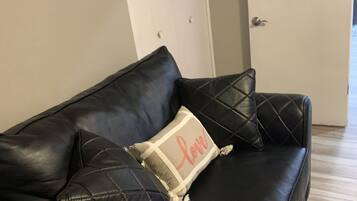 A black leather sofa with a quilted pattern and a cushion with a tag that reads "love".