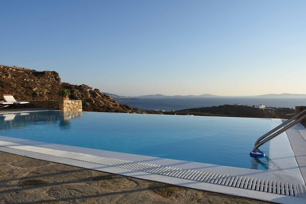 En säsongsöppen utomhuspool, parasoller och solstolar