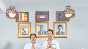 A reception desk with a sign reading "RECEPTION," two framed portraits on the wall, and flags of Cambodia and the United States. - Calao Kep Residence Hotel (Kep)