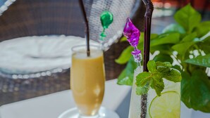 Two drinks on a table with a wicker chair and a white umbrella in the background. - Calao Kep Residence Hotel (Kep)