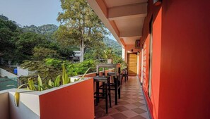 A balcony with a checkered floor, surrounded by greenery and a view of a hilly landscape. - Calao Kep Residence Hotel (Kep)