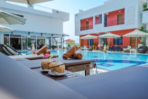A poolside area with lounge chairs, a pool, and a building with red and white exterior. - Calao Kep Residence Hotel (Kep)
