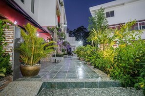 A courtyard with a tiled floor, potted plants, and a brick wall. - Calao Kep Residence Hotel (Kep)