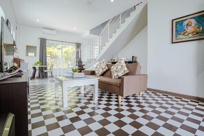 A modern living room with a checkered floor, a sofa with patterned cushions, a coffee table, and a staircase. - Calao Kep Residence Hotel (Kep)