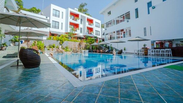 A modern hotel with a swimming pool, outdoor seating, and a view of the surrounding buildings. - Calao Kep Residence Hotel (Kep)