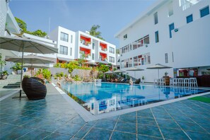 A modern hotel with a swimming pool, outdoor seating, and a view of the surrounding buildings. - Calao Kep Residence Hotel (Kep)