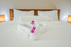 A neatly made bed with white linens and a decorative towel with pink flowers. - Calao Kep Residence Hotel (Kep)