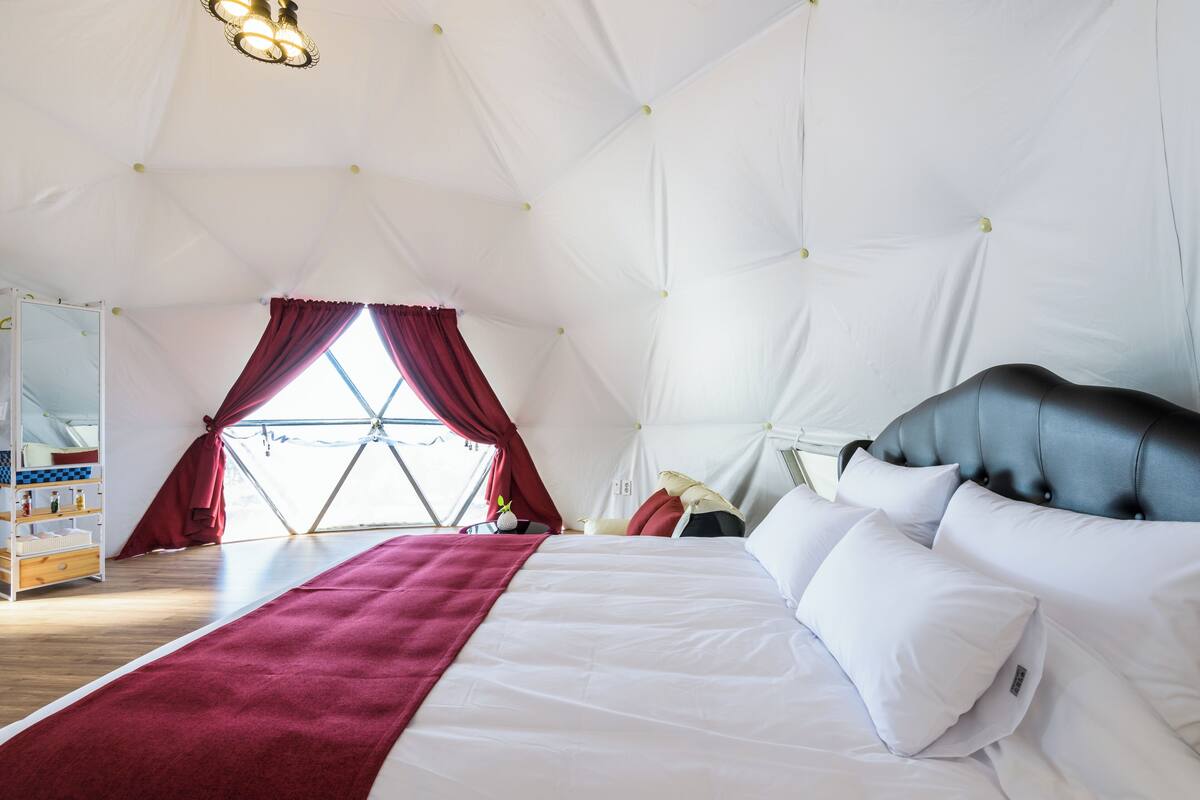 Une chambre spacieuse avec un grand lit, une armoire et une fenêtre avec des rideaux.
