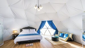 Ein Zelt-Schlafzimmer mit Bett, Nachttisch und Sitzecke.
