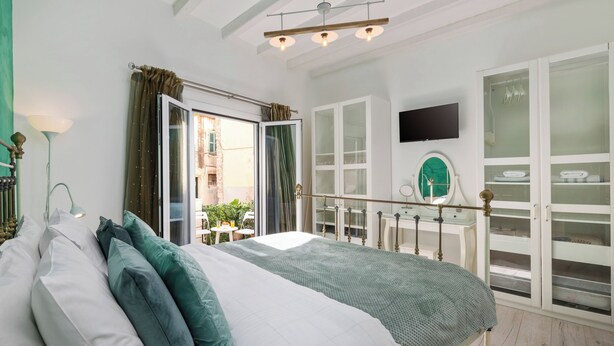 Ein Schlafzimmer mit Bett, Schreibtisch, Stuhl, Fernseher und einem Balkon mit Blick.