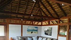 A cozy room with a wooden table, benches, and a sofa. - Aloha 1 (Ponta d'Ouro)