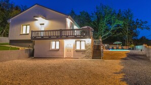 Ein modernes, zweistöckiges Haus mit Balkon, Steineingang und gut beleuchteter Auffahrt.