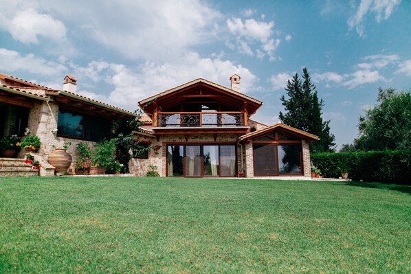 A two-story house with a balcony, large windows, and a well-maintained lawn.