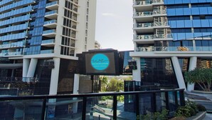 A modern building with a sign that reads "accommodate GOLD COAST Stay with us." - Family 2 Bedroom Ocean unit at Circle on Cavill (Surfers Paradise)