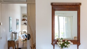 Une salle de bain avec un meuble-lavabo en bois, un miroir et un vase rempli de fleurs blanches.
