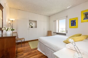 A bedroom with a bed, bedside table, lamp, and a window.