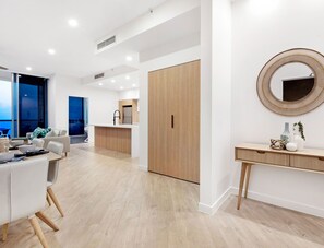 Un salon moderne avec un coin repas, une armoire en bois et un grand miroir rond accroché au mur.