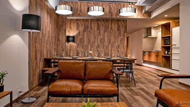 A modern dining area with a wooden wall, leather seating, and pendant lighting. - American Vintage Suite (Tokyo)