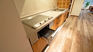 A modern kitchen with a built-in stove, a sink, and wooden cabinetry. - American Vintage Suite (Tokyo)