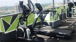 A gym with cardio equipment including a treadmill and an elliptical machine, with a city view in the background. - Premier Executive Apartment - The Ivy, East Legon (East Legon)