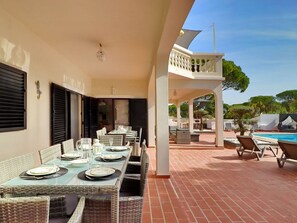 A dining area with a table set for four, outdoor seating, and a pool.