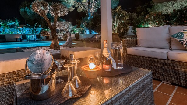 An outdoor seating area with a pool, wicker furniture, and a table with candles and glassware. - Quinta Pequena is a traditional,  3 bedroom Apartment/Villa near Vale Do Lobo. (Quinta Pequena Almancil,)