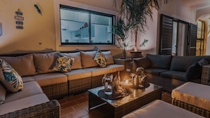 A cozy living room with wicker sofas, a coffee table with decorative items, a large window, and a potted plant. - Quinta Pequena is a traditional,  3 bedroom Apartment/Villa near Vale Do Lobo. (Quinta Pequena Almancil,)
