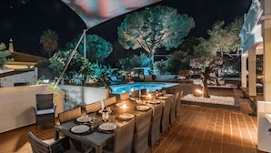 An outdoor dining area with a pool, wicker furniture, and ambient lighting. - Quinta Pequena is a traditional,  3 bedroom Apartment/Villa near Vale Do Lobo. (Quinta Pequena Almancil,)