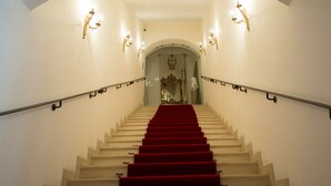 Un magnifique escalier, avec un tapis rouge, des murs blancs et des appliques murales décoratives.