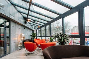A modern interior with a glass ceiling, seating area, and potted plants. - Hotel Krowodrza  Krakow (Kraków)