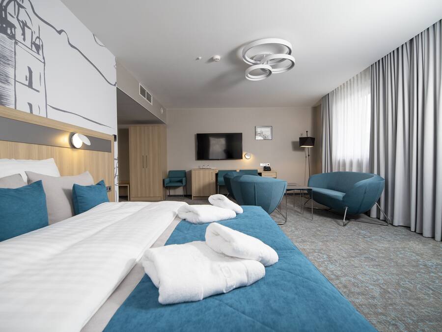 Camera d'albergo moderna con un ampio letto, una scrivania, una sedia e un televisore.