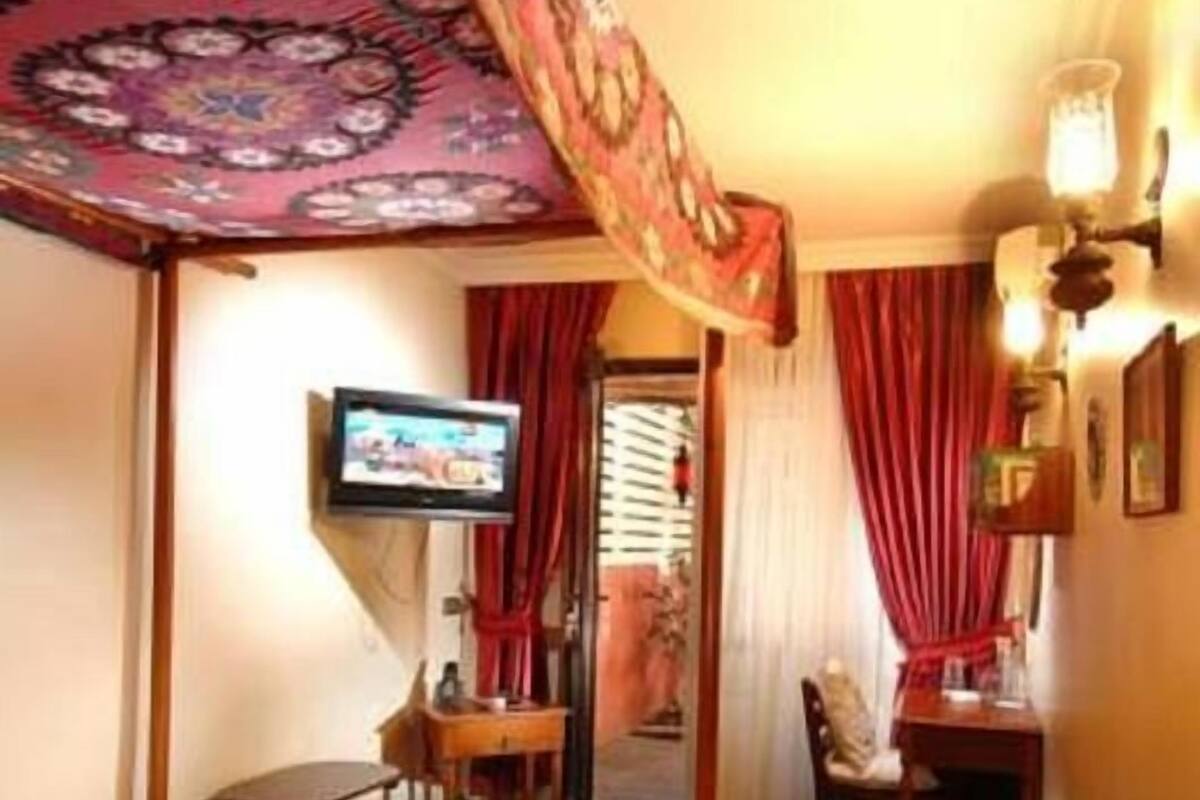A hotel room with a bed, a desk, a chair, a television, and a curtain.