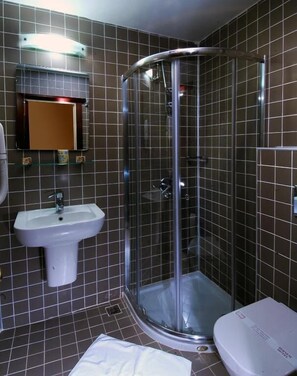 A bathroom with a glass-enclosed shower, a sink, and a toilet. - Şebnem Hotel (Istanbul)