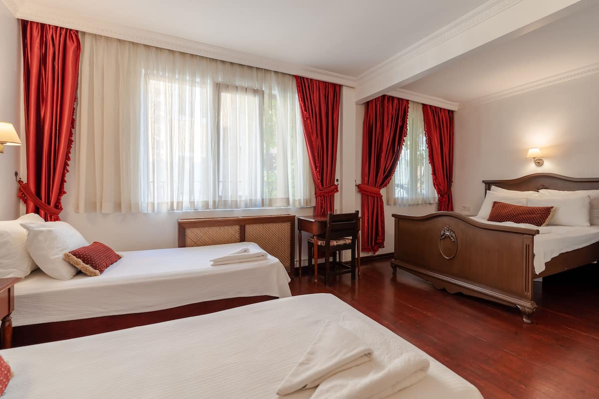 A hotel room with two beds, a desk, and a chair.
