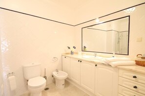 Un baño con inodoro, bidé y un espejo grande sobre el lavabo.