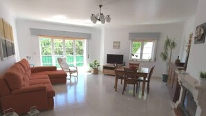 Una sala de estar amplia con un sofá modular, una mesa de comedor con sillas, una chimenea y un televisor.