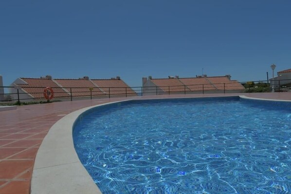 Una piscina con un borde empavedado y una valla.