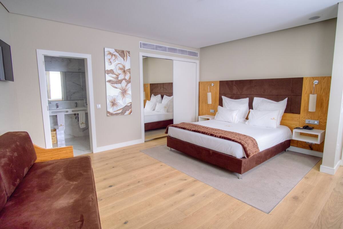 A modern bedroom with a large bed, a wooden headboard, a bedside table, and a wardrobe.